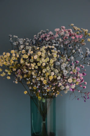A tall vase filled with vibrant wildflowers in soft pastel tones against a muted background.