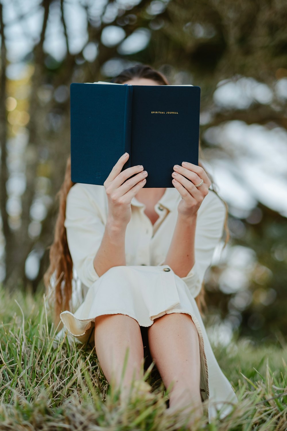 uma mulher sentada na grama lendo um livro