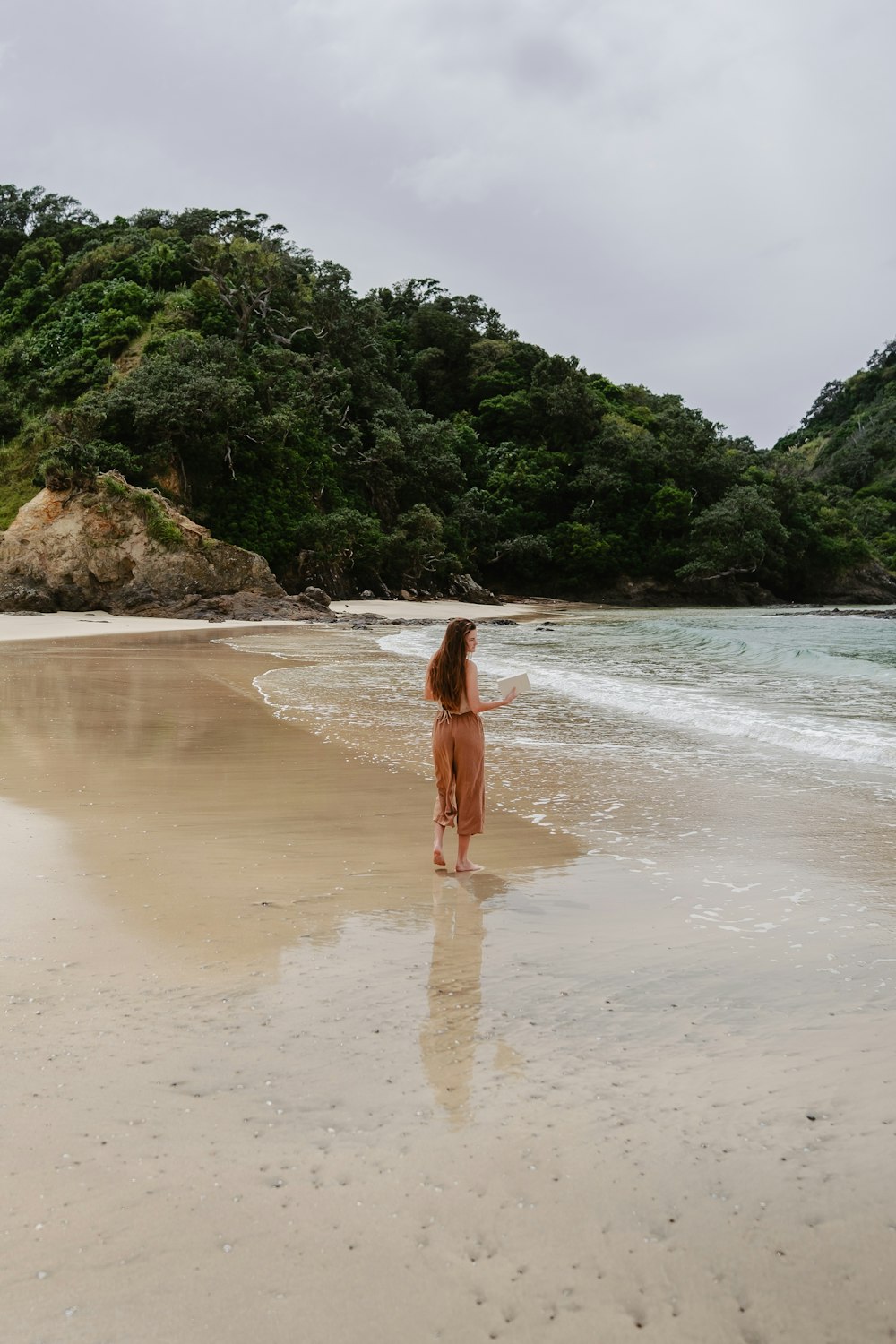 uma mulher em pé no topo de uma praia de areia