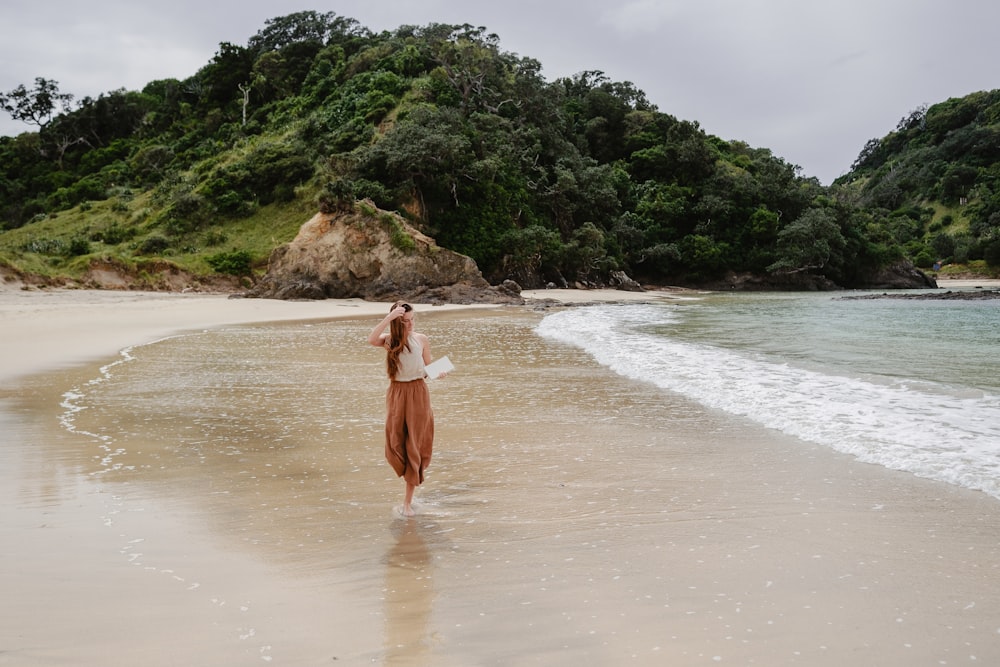 Una donna in piedi sulla cima di una spiaggia sabbiosa