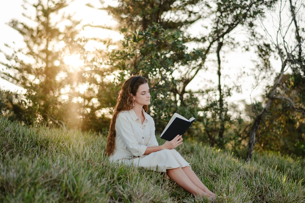 a woman sitting in the grass reading a book