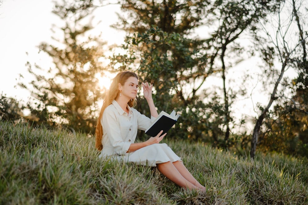 a woman sitting in the grass reading a book