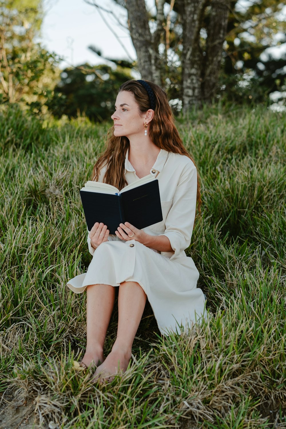 a woman sitting in the grass reading a book