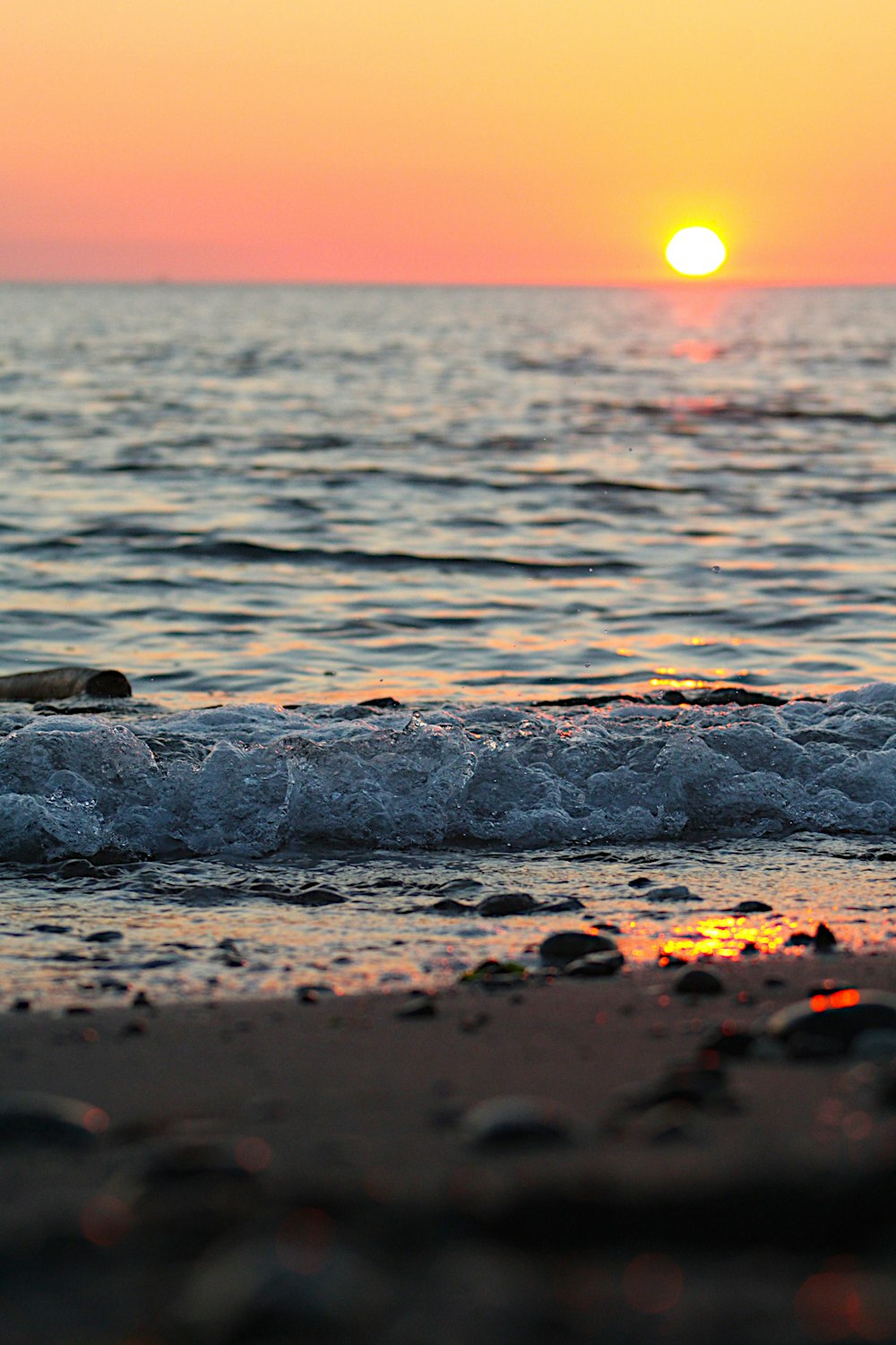 the sun is setting over the water at the beach