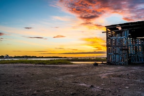 A detailed Rust base built with wooden walls and metal reinforcements under a sunset sky.
