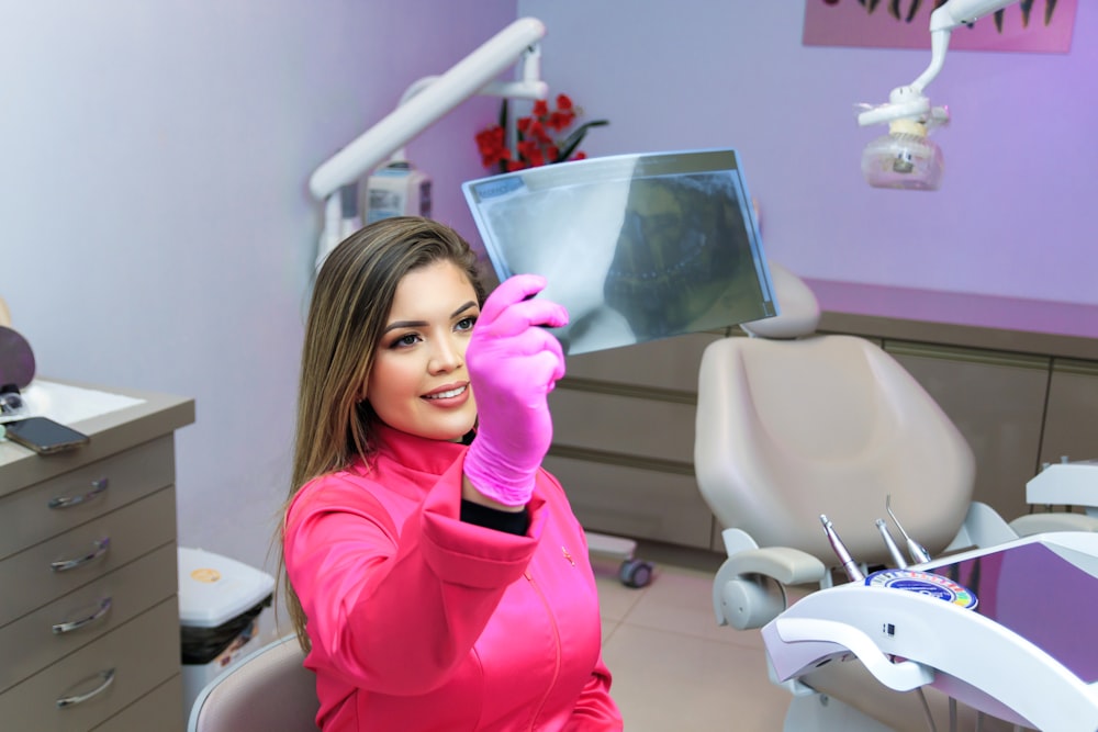 a woman sitting in a dentist chair holding up a mirror