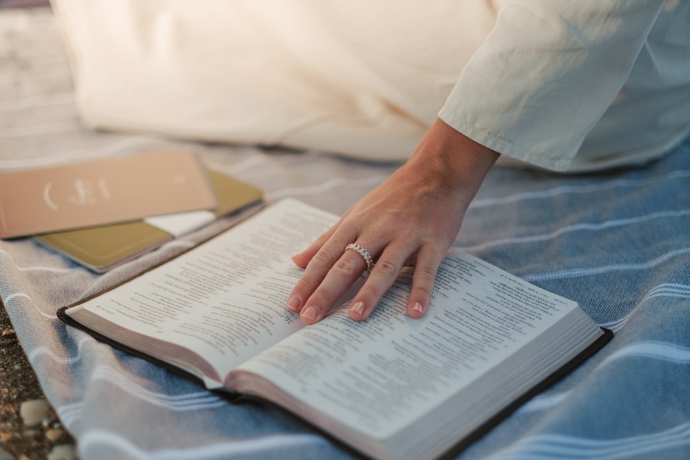 a woman is reading a book on a bed