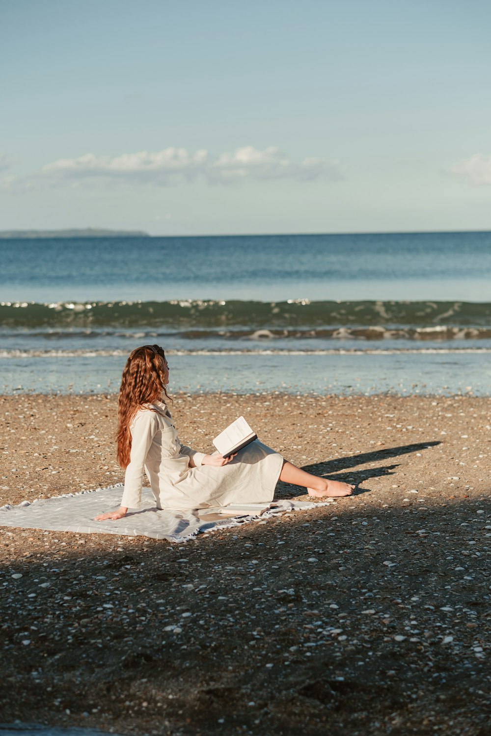 a woman sitting on a beach reading a book