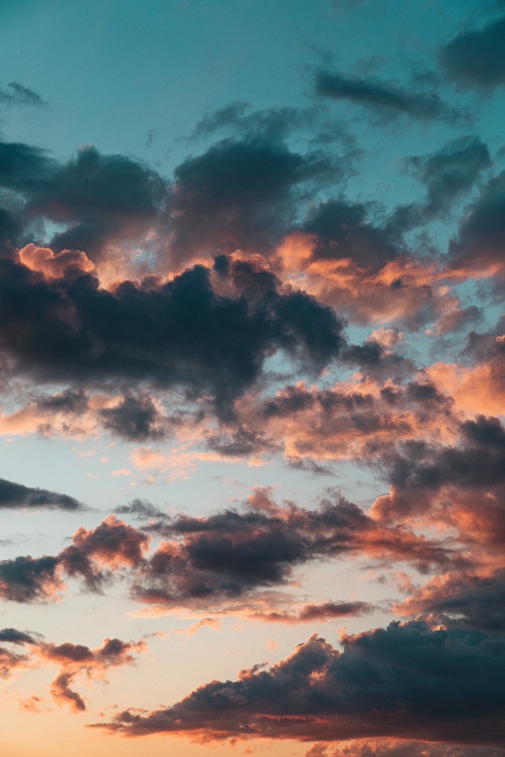 a plane flying through a cloudy sky at sunset