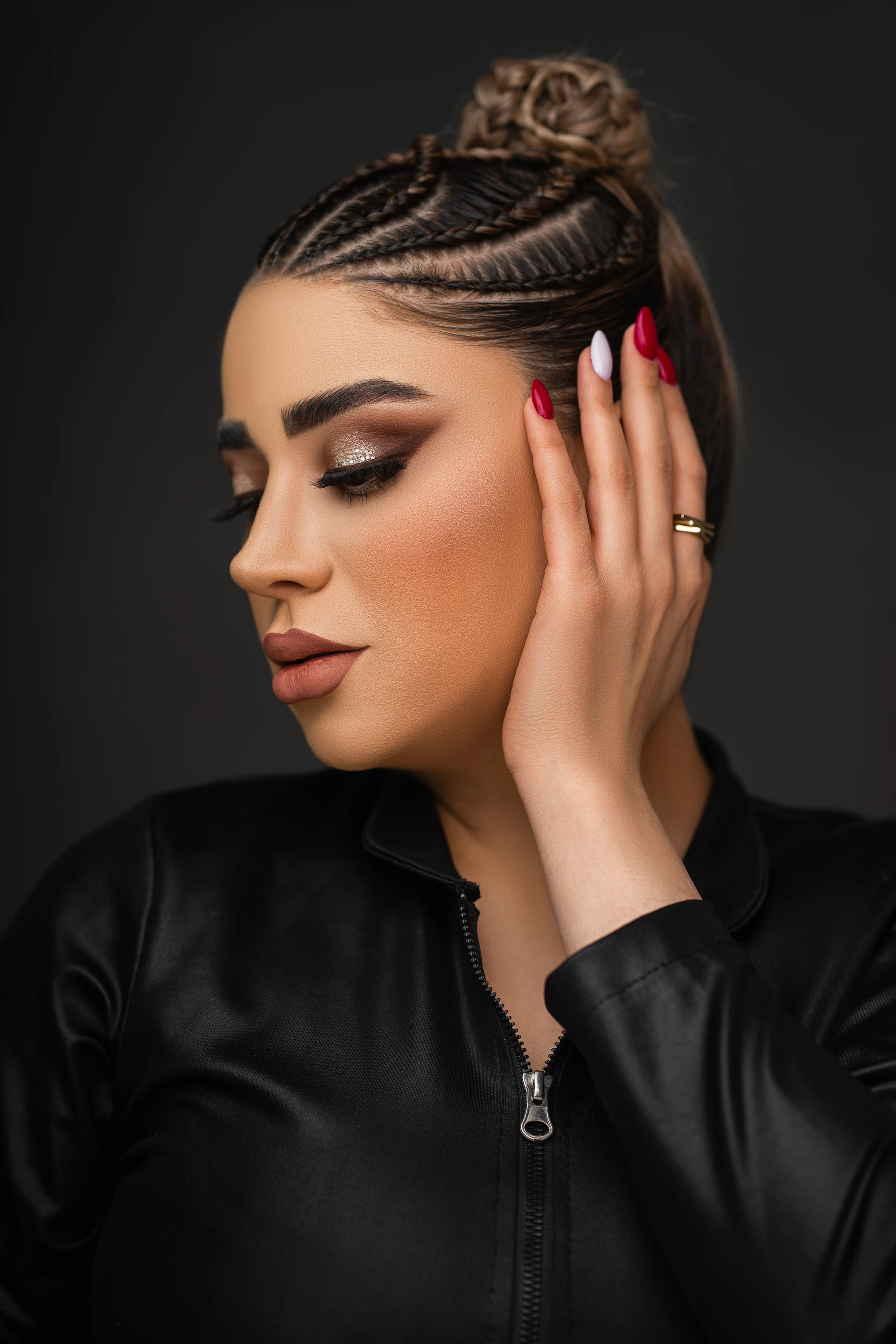 a woman with braids and red nails holding her hand up to her ear