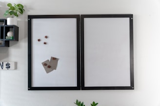 a white wall with a black frame and a picture of a piece of paper on