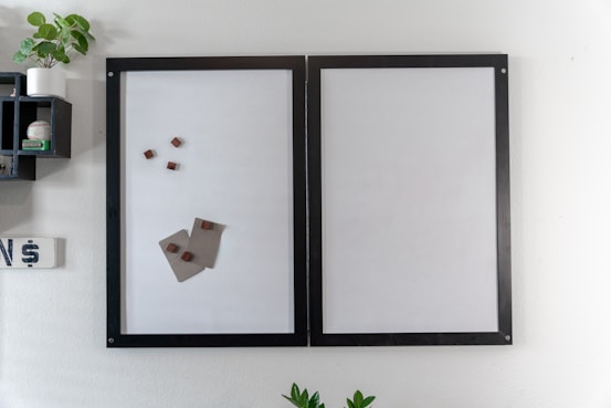 a white wall with a black frame and a picture of a piece of paper on