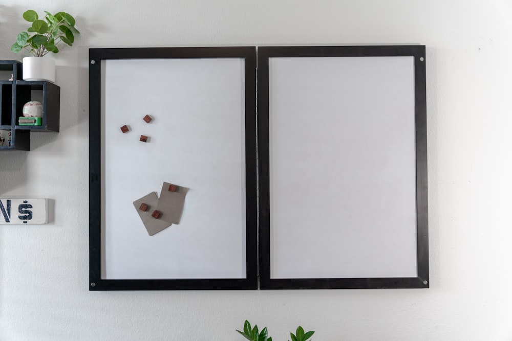 uma parede branca com uma moldura preta e uma imagem de um pedaço de papel em