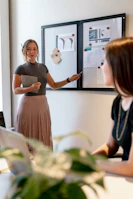 An older woman mentoring a younger member, pointing at notes in a bright, welcoming workspace.
