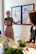 A woman happily presenting her business plan on a whiteboard in a bright meeting room.