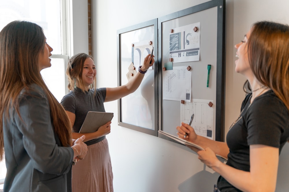 a group of women standing around a white board