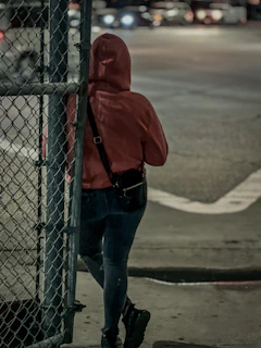 Purple-accented hoodie draped over a chain-link fence with urban skyline in the background at dusk