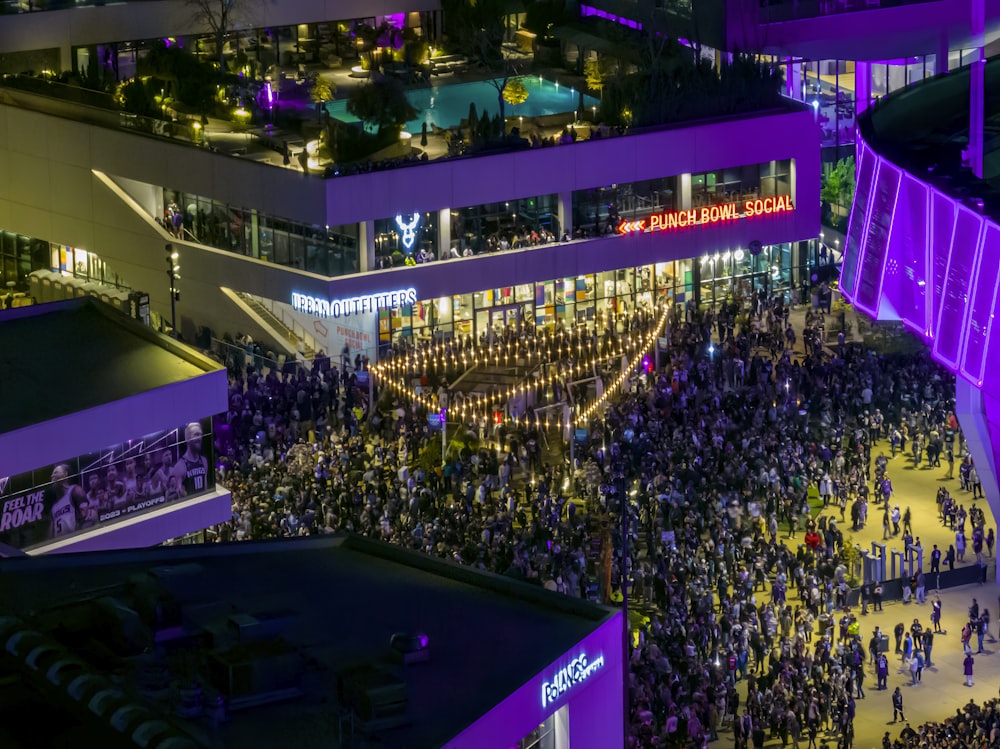 a crowd of people standing around a building at night