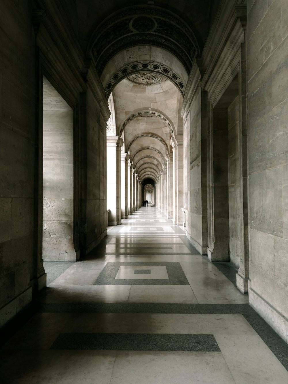 a long hallway with columns and a clock on the wall