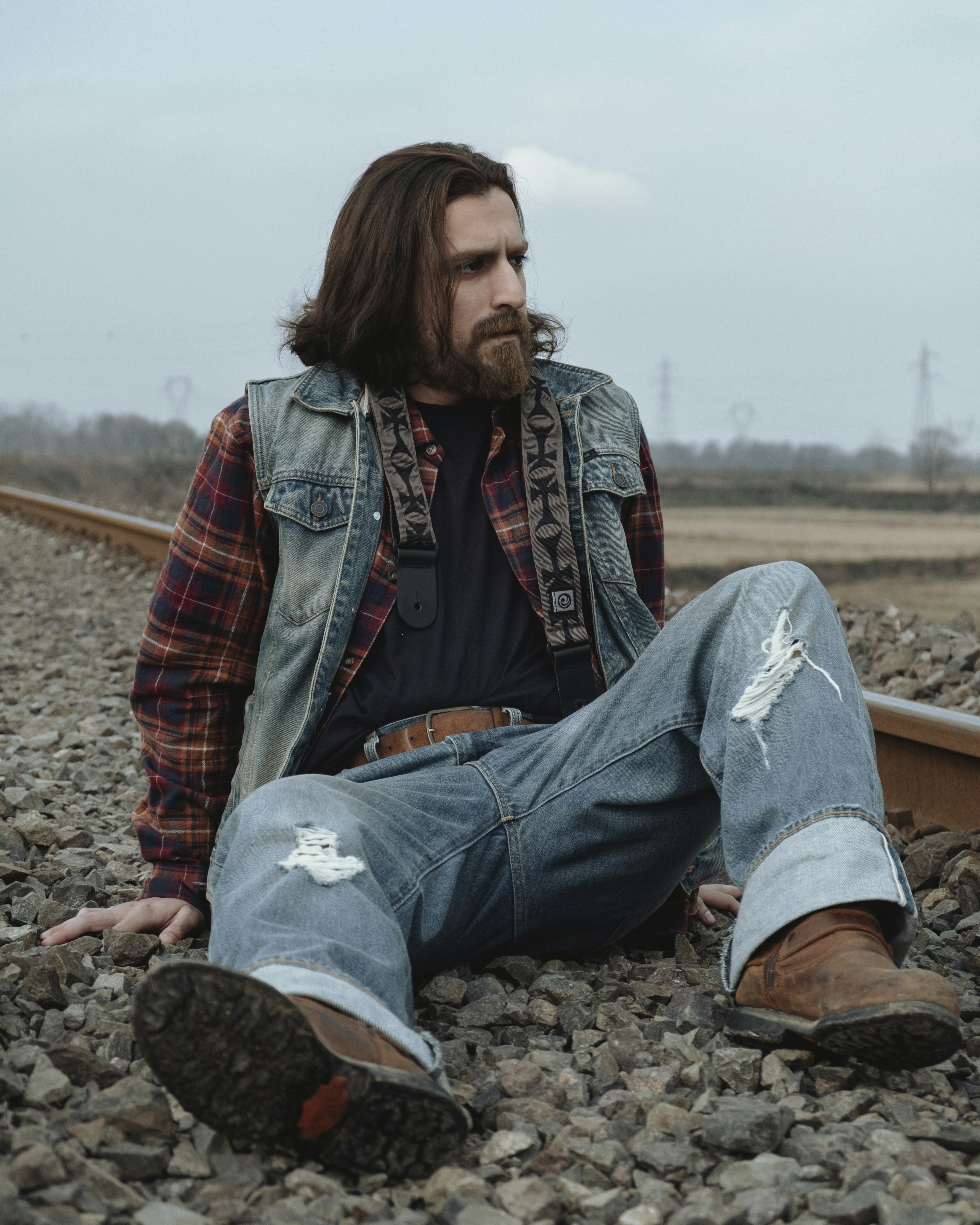 a man with long hair sitting on a train track