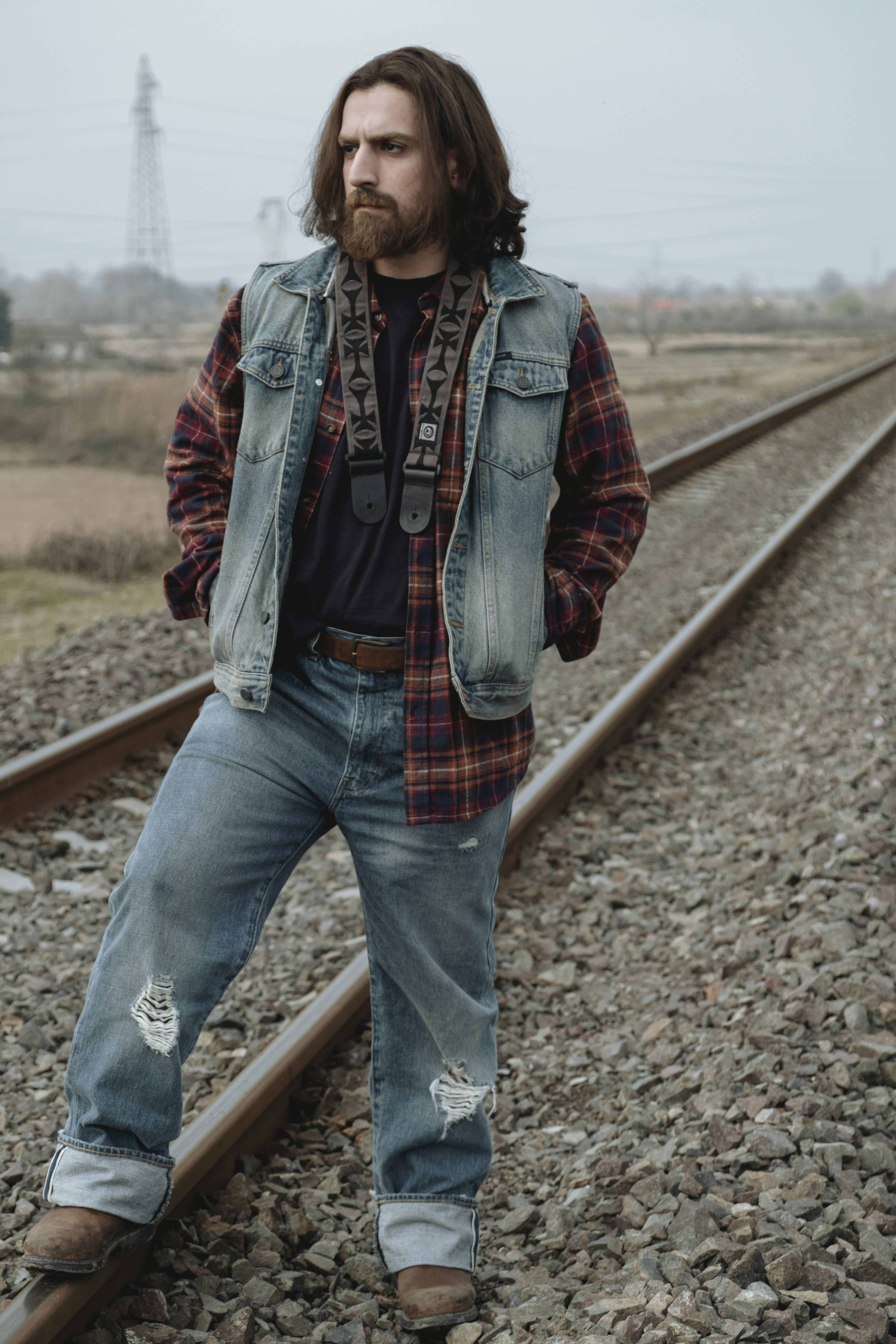a man standing on a train track with his hands in his pockets