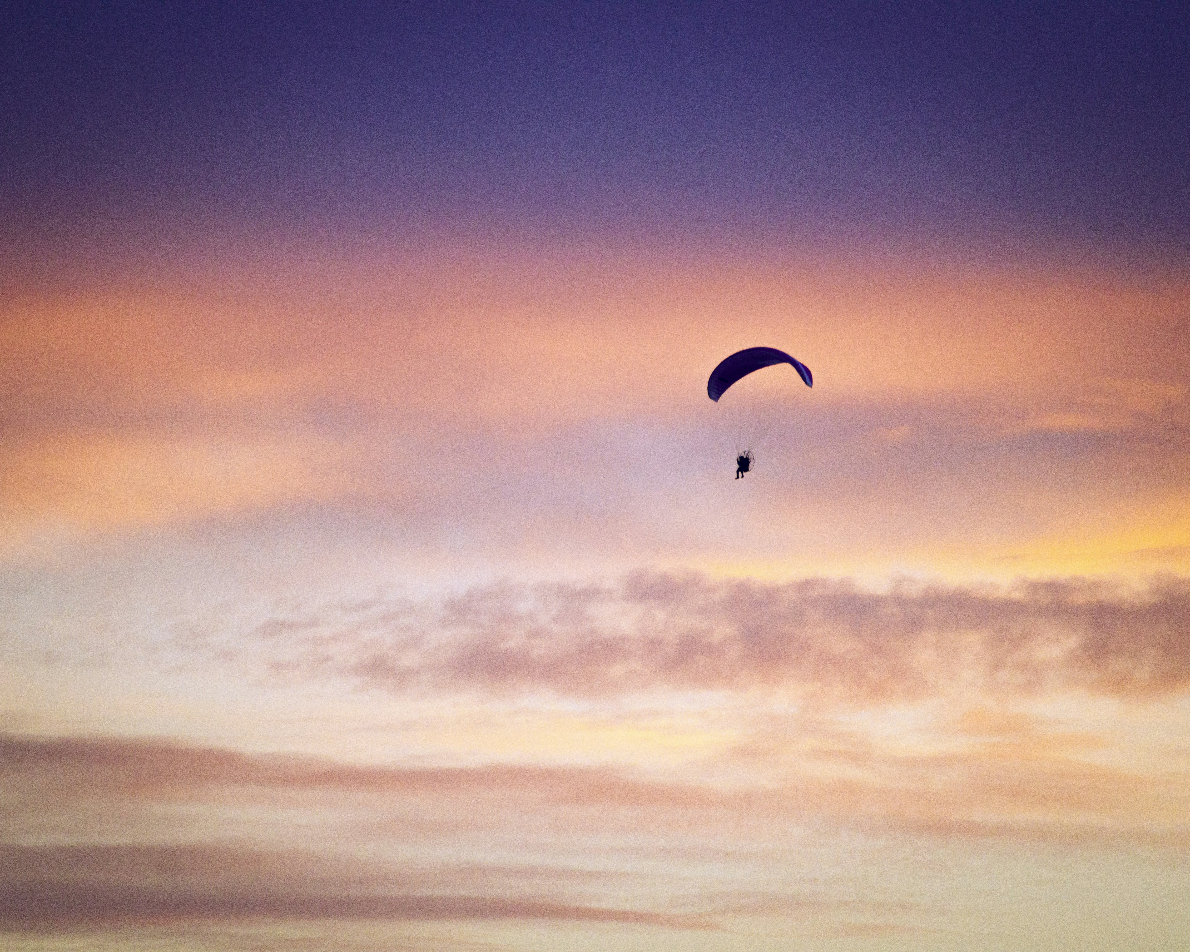 a paraglider flying in the sky at sunset