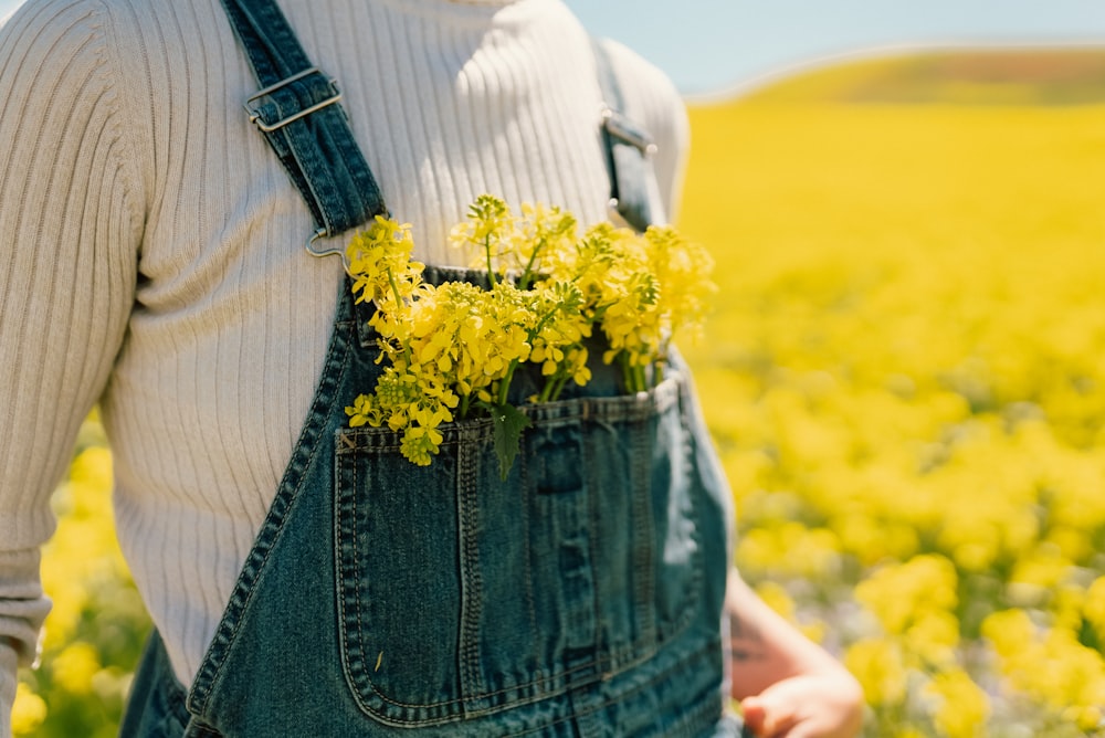 a person wearing overalls and holding a bunch of flowers