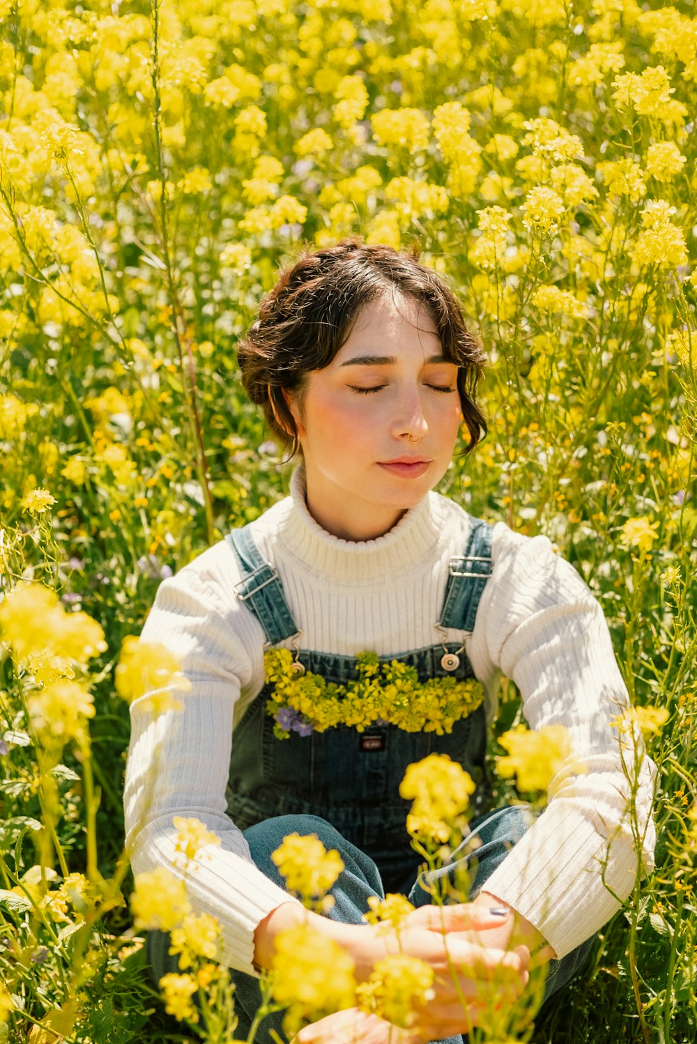 a young girl sitting in a field of yellow flowers