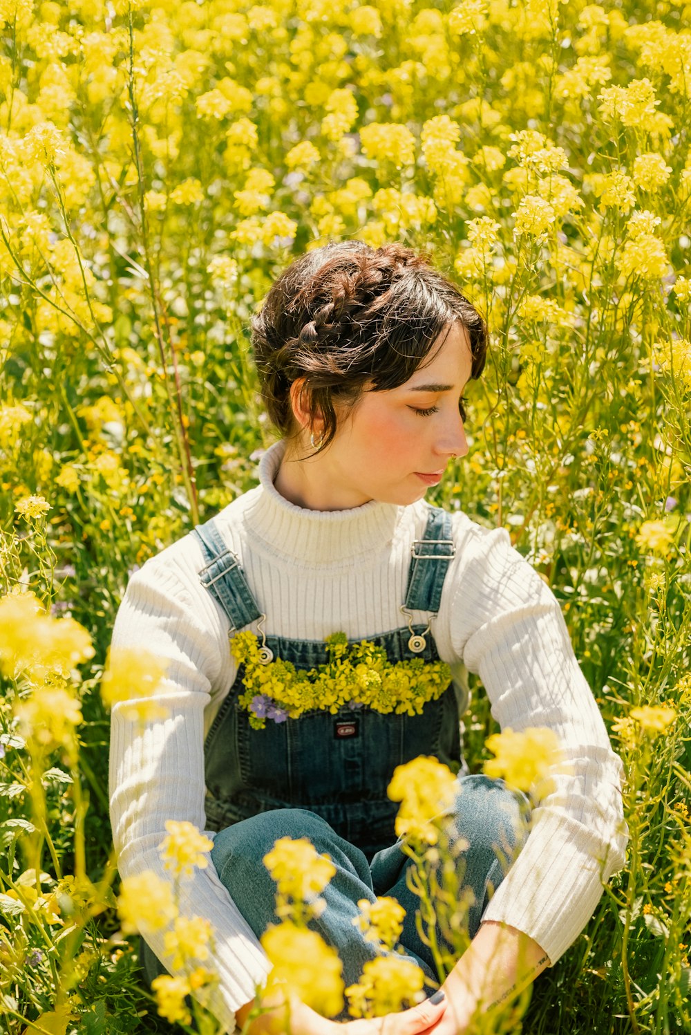 a young girl sitting in a field of yellow flowers