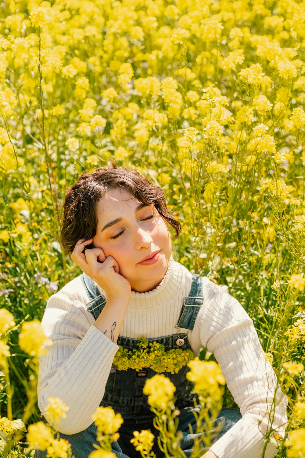 a woman sitting in a field of yellow flowers