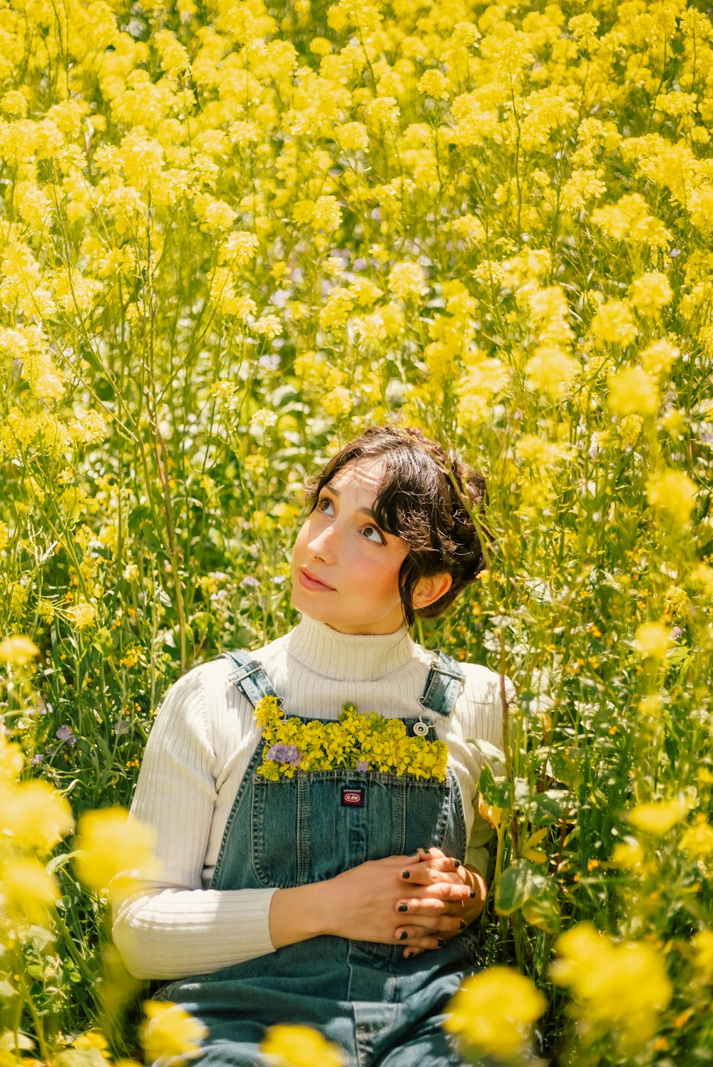 uma mulher sentada em um campo de flores amarelas