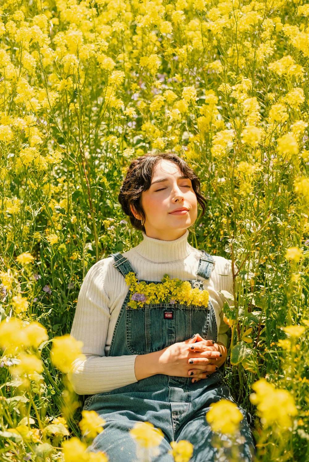 a woman sitting in a field of yellow flowers