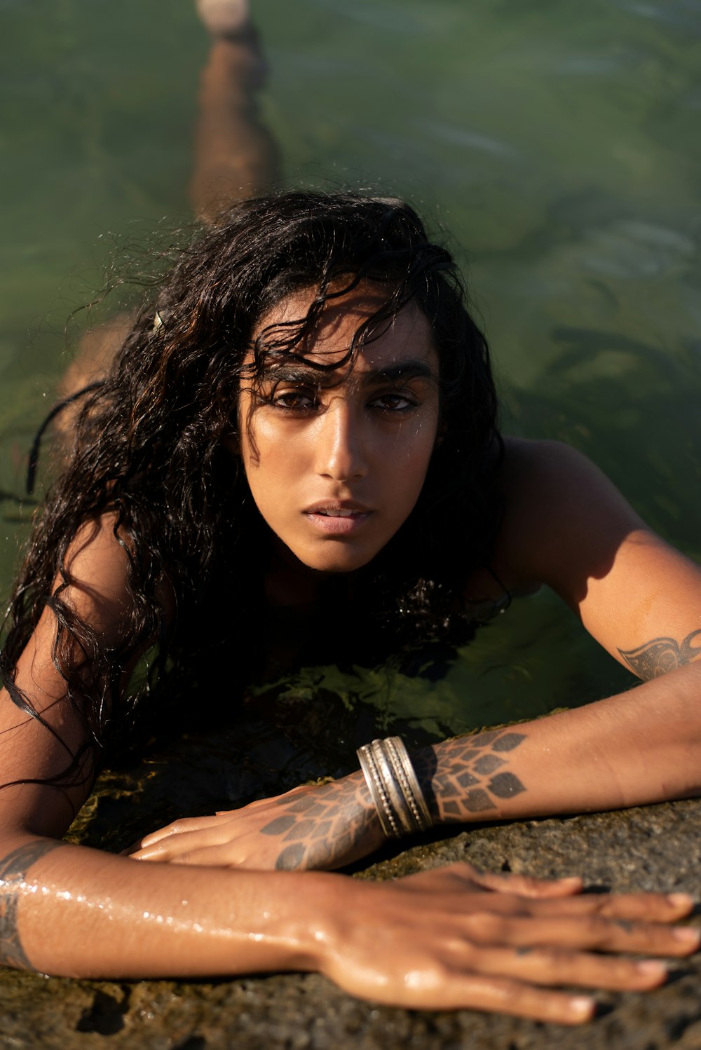 a woman in a body of water with tattoos on her arms