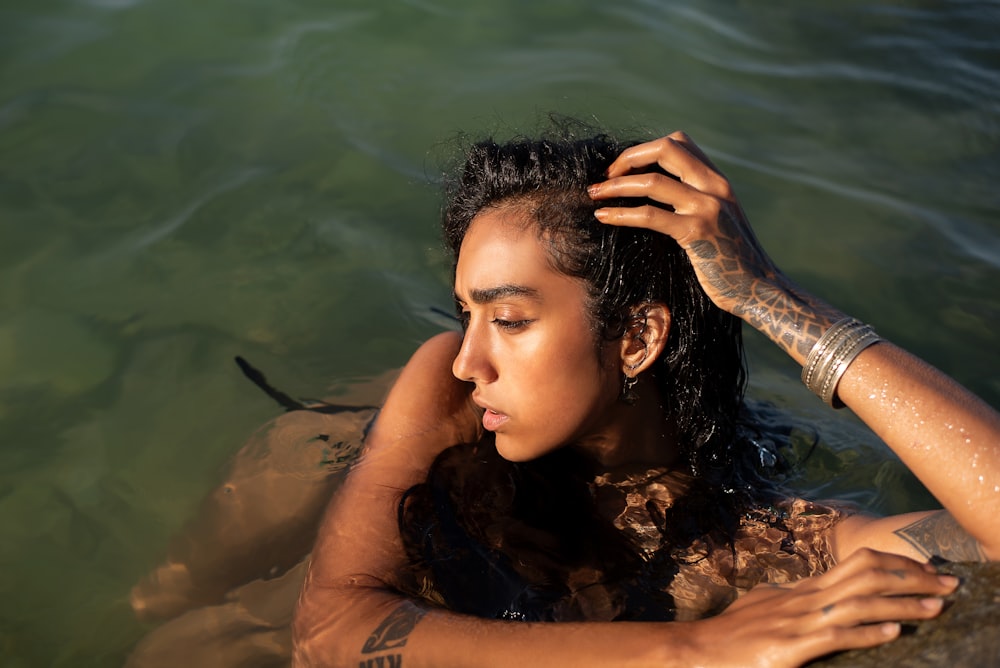 a woman in a body of water with her hands on her head