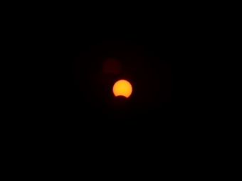 A solar eclipse with a partially obscured sun, leaving a crescent shape in a dark sky.