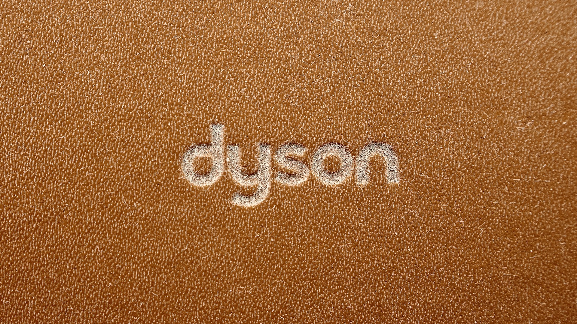 the word dyson written on a brown leather surface