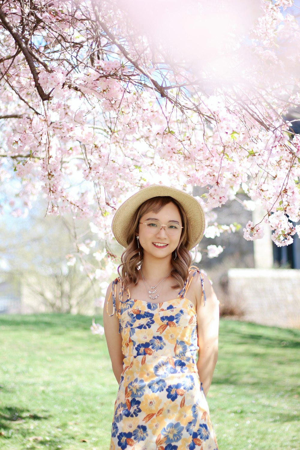 a woman standing under a tree with a hat on