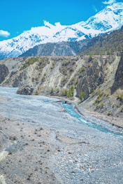 A cinematic 4k image of a crystal-clear blue river winding through snow-capped mountains under a deep midnight sky.