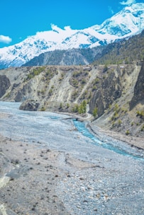 A cinematic 4k image of a crystal-clear blue river winding through a lush mountain valley under a bright sky.