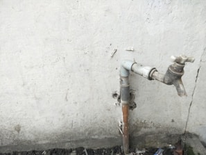 An old faucet being removed with rust and mineral deposits visible.