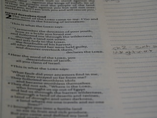 A close-up of hands holding an open Bible with notes.