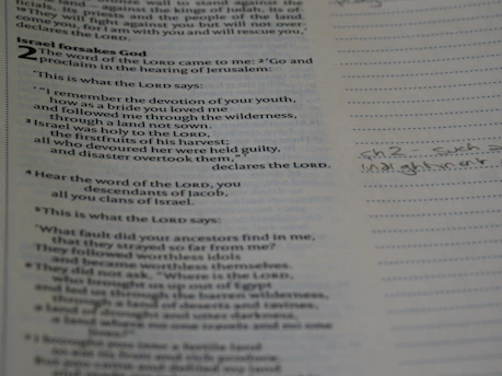 A close-up of hands gently holding a well-worn Bible with notes tucked inside.
