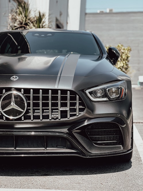 A sleek black luxury car gleaming under the California sun, freshly detailed on a palm-lined street.