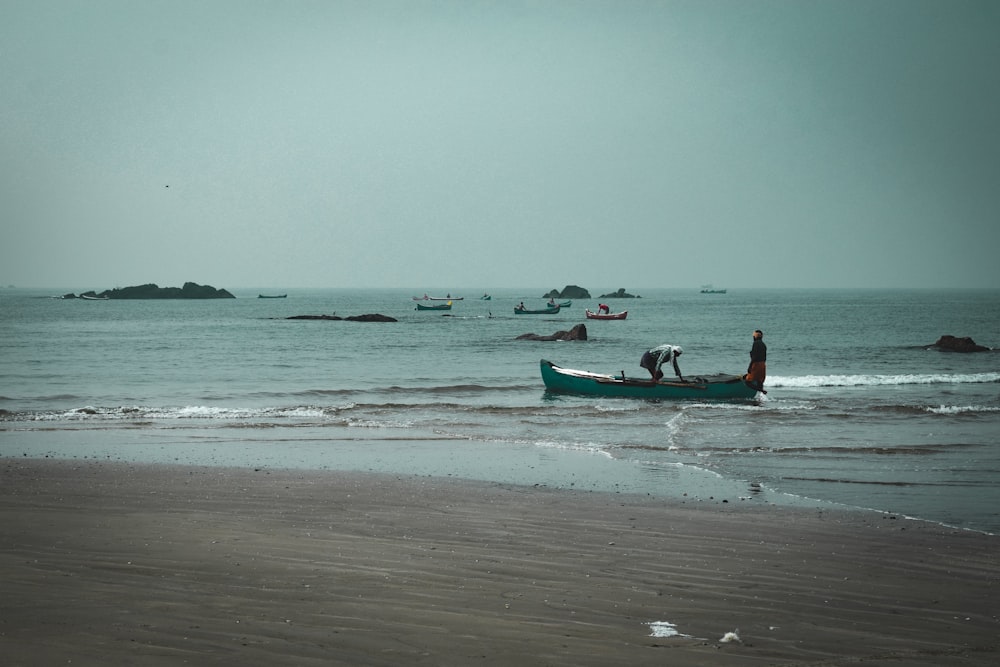 a couple of people in a small boat on a beach