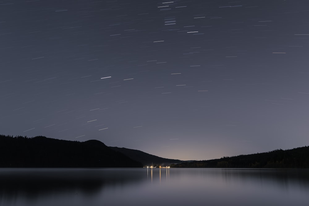the night sky is lit up over a lake