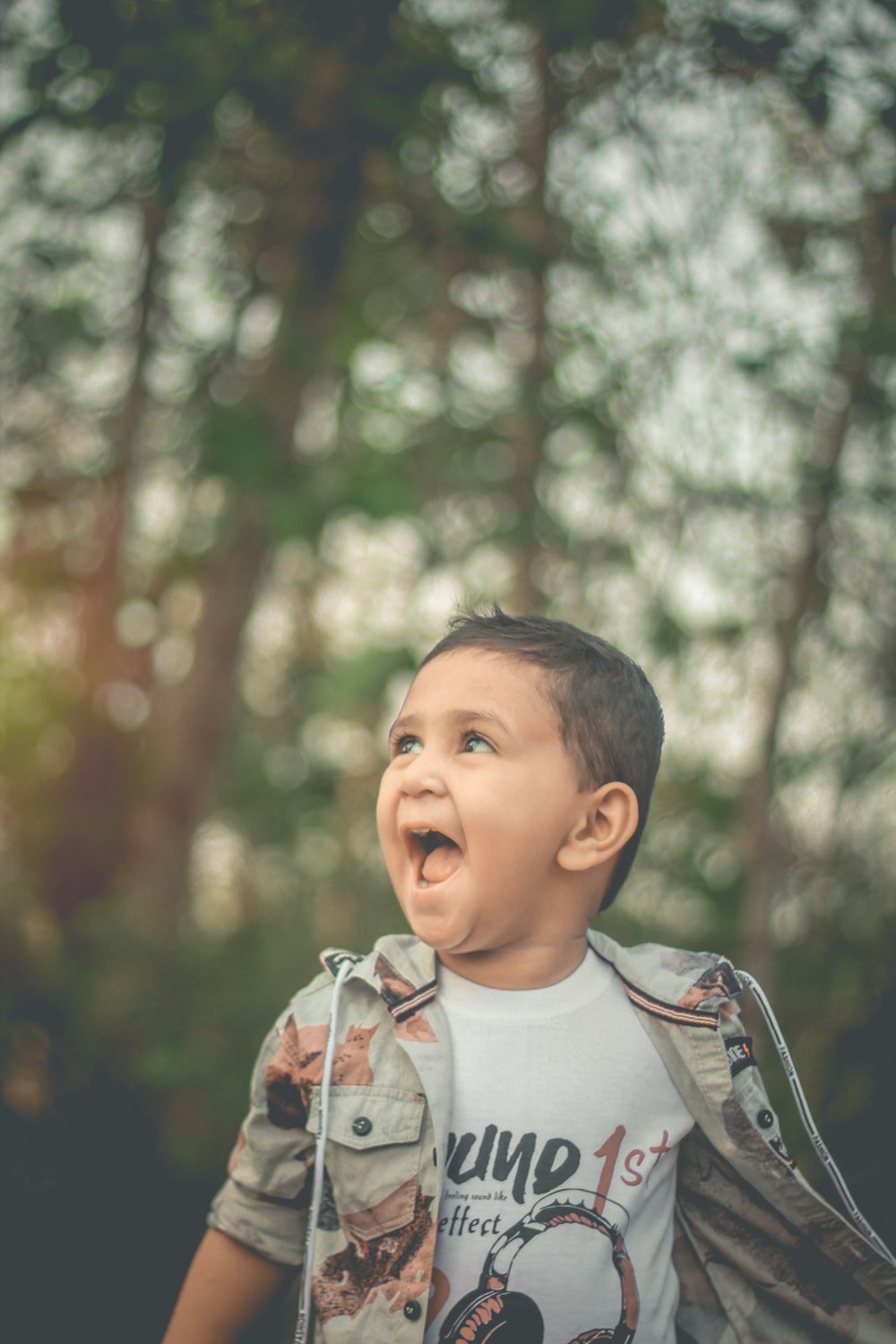 a young boy with his mouth open in the woods