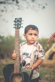 a young boy holding a guitar in his hands