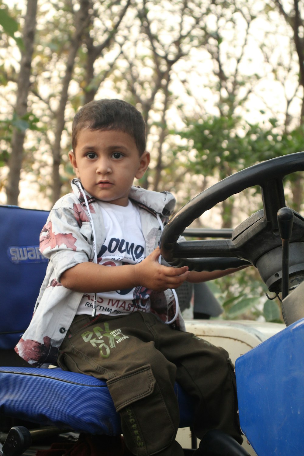 a young boy sitting on the back of a blue vehicle