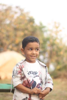 A cheerful boy wearing a cream gold nehru jacket, standing proudly with hands in pockets.
