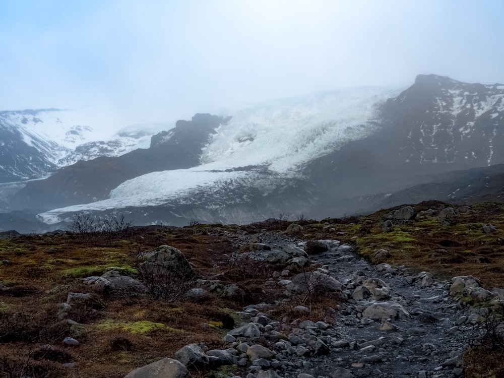 a rocky path leading to a mountain covered in snow